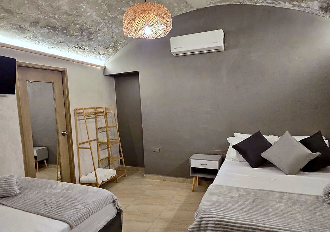 A bedroom with two beds, a ladder, a bedside table, and a hanging light fixture.