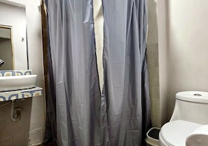 Ein Badezimmer mit Duschvorhang, Waschbecken und Fliesenrückwand mit Muster sowie Toilette.