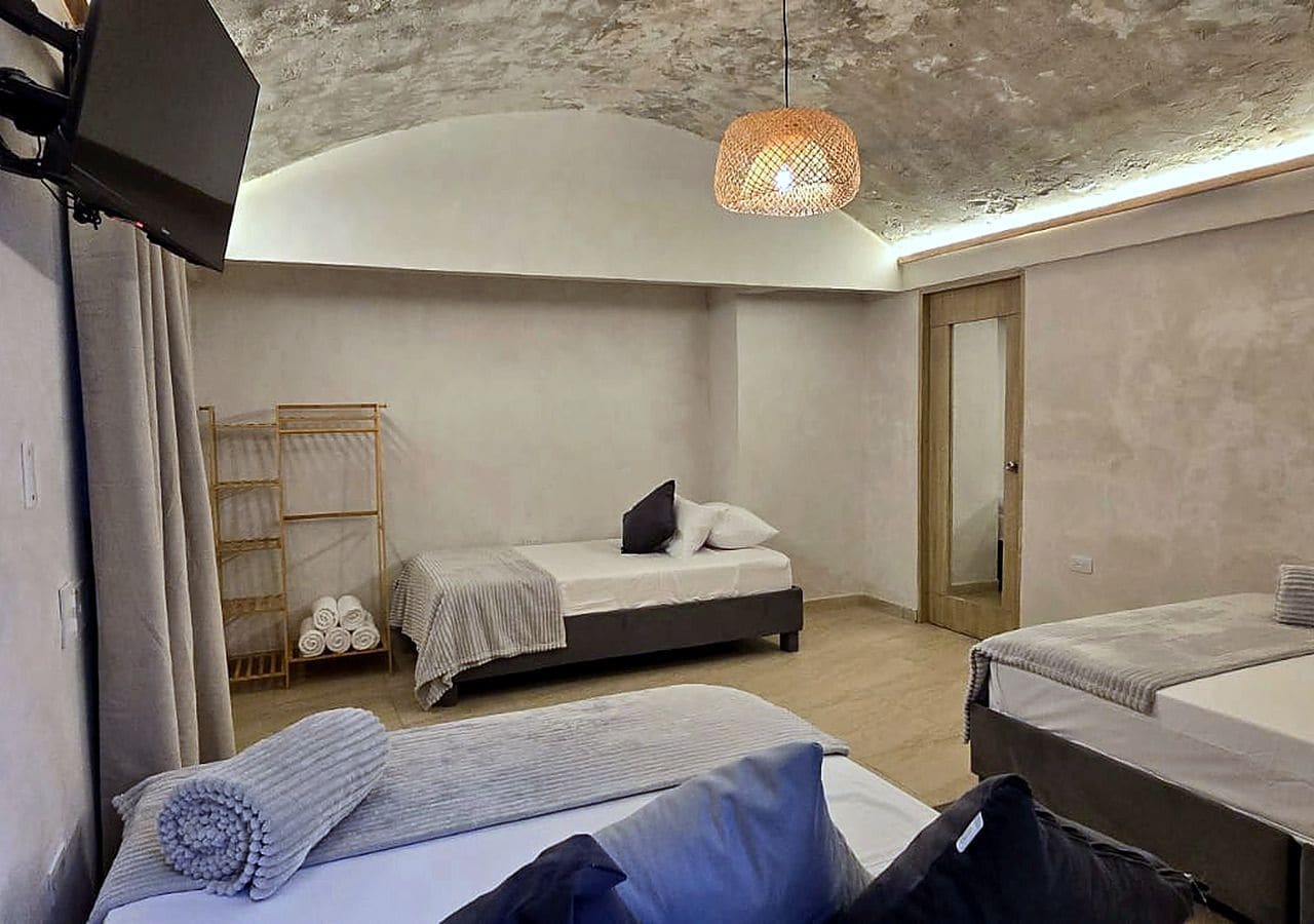 A modern bedroom with two beds, a wooden ladder, and a hanging light fixture.