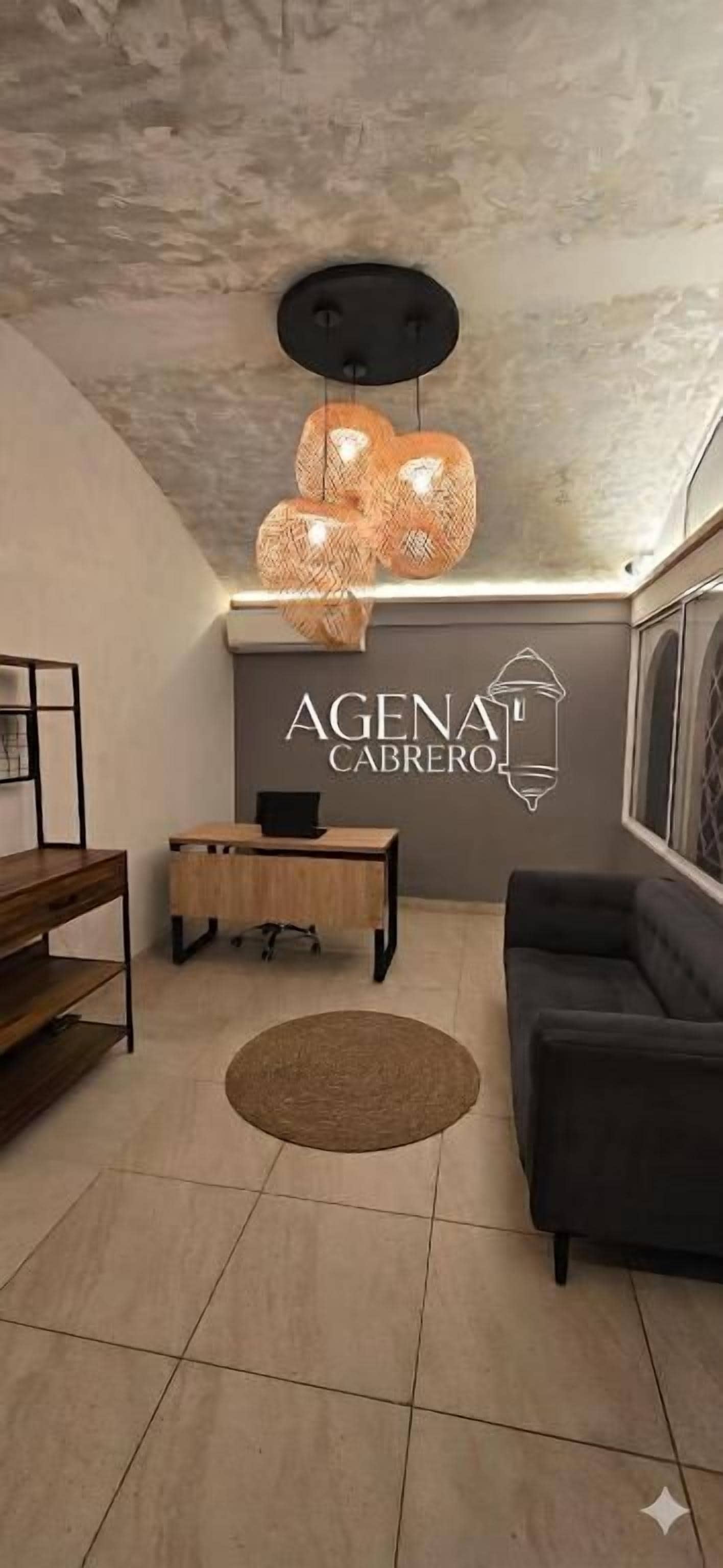 Un salon moderne comprenant un canapé, une table basse, un tapis et un panneau mural portant l’inscription « AGENAT CABRERO ».