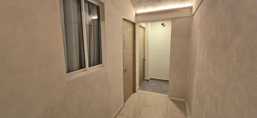 A narrow hallway with a window, a door, and a light fixture on the ceiling.