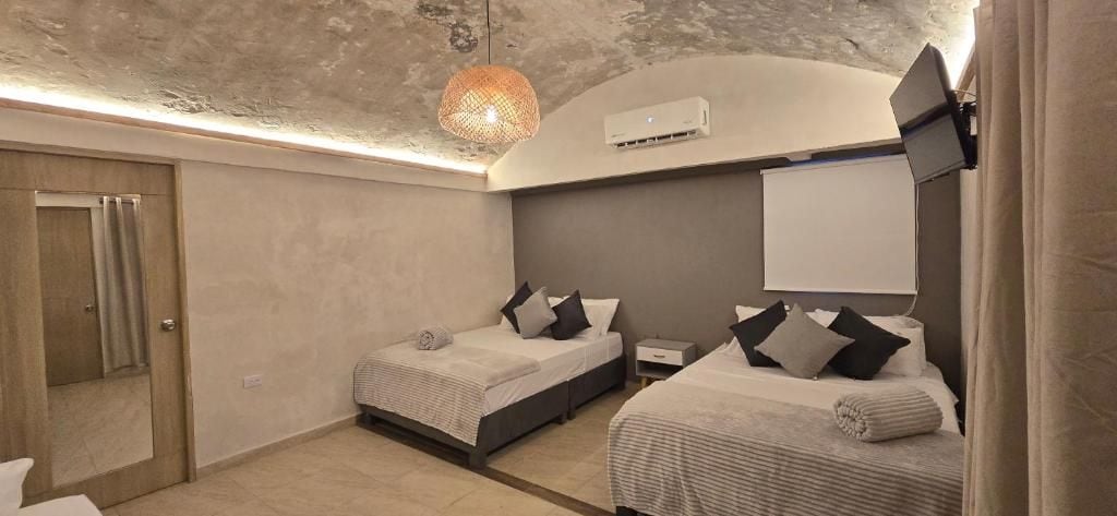 A bedroom with two beds, a ceiling fan, an air conditioning unit, and a mounted television.