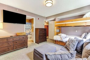 A bedroom with a bunk bed, a dresser, a television, and a sign on the wall. - Upscale Winterplace 3BR | Steps to Ski Access (Ludlow)