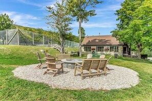 A patio area with Adirondack chairs and a round table, surrounded by a gravel circle. - Upscale Winterplace 3BR | Steps to Ski Access (Ludlow)