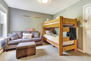 A room with a bunk bed, a sofa, and an ottoman. - Upscale Winterplace 3BR | Steps to Ski Access (Ludlow)