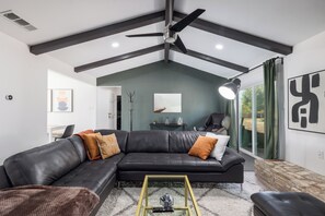 A modern living room with a sectional sofa, a coffee table, and a ceiling fan. - 3BR Retreat in Austin — Massage chair & Firepit (Austin)