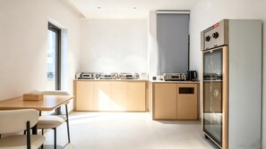 Una cocina moderna con zona de comedor, equipada con cafetera, tostadora y refrigerador.
