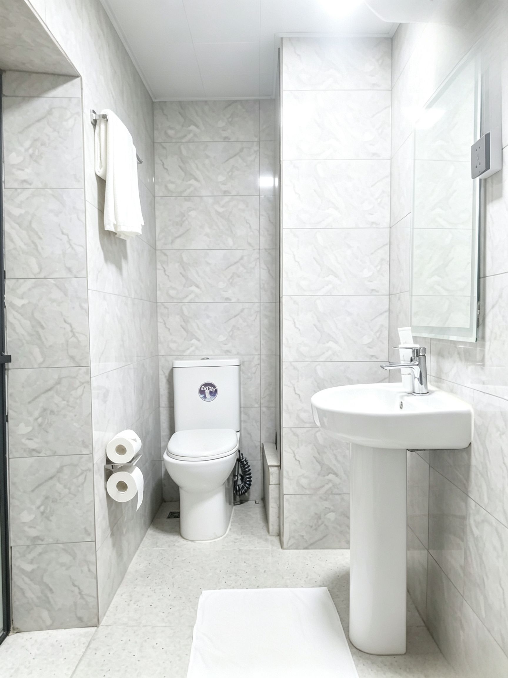 Un baño moderno con inodoro, lavabo y paredes de mármol.