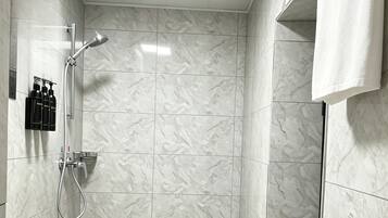 Un baño con un lavamanos blanco, ducha con cabezal de ducha de mano y un inodoro.
