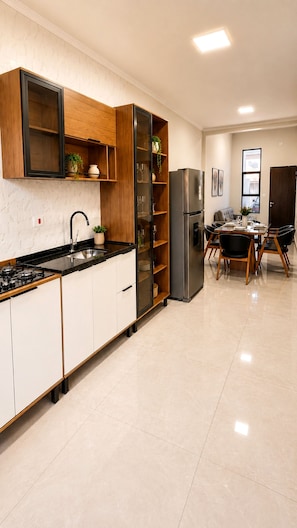 A modern kitchen with a gas stove, stainless steel refrigerator, and wooden cabinets.