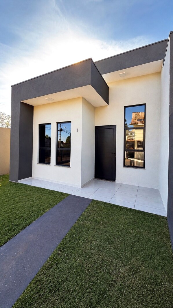 A modern two-story house with a flat roof, large windows, and a dark exterior.