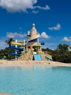 Parque acuático con una torre central, varias toboganes y una piscina.