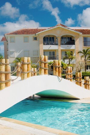 Un hotel con piscina, un puente y un edificio con tejado de azulejos.