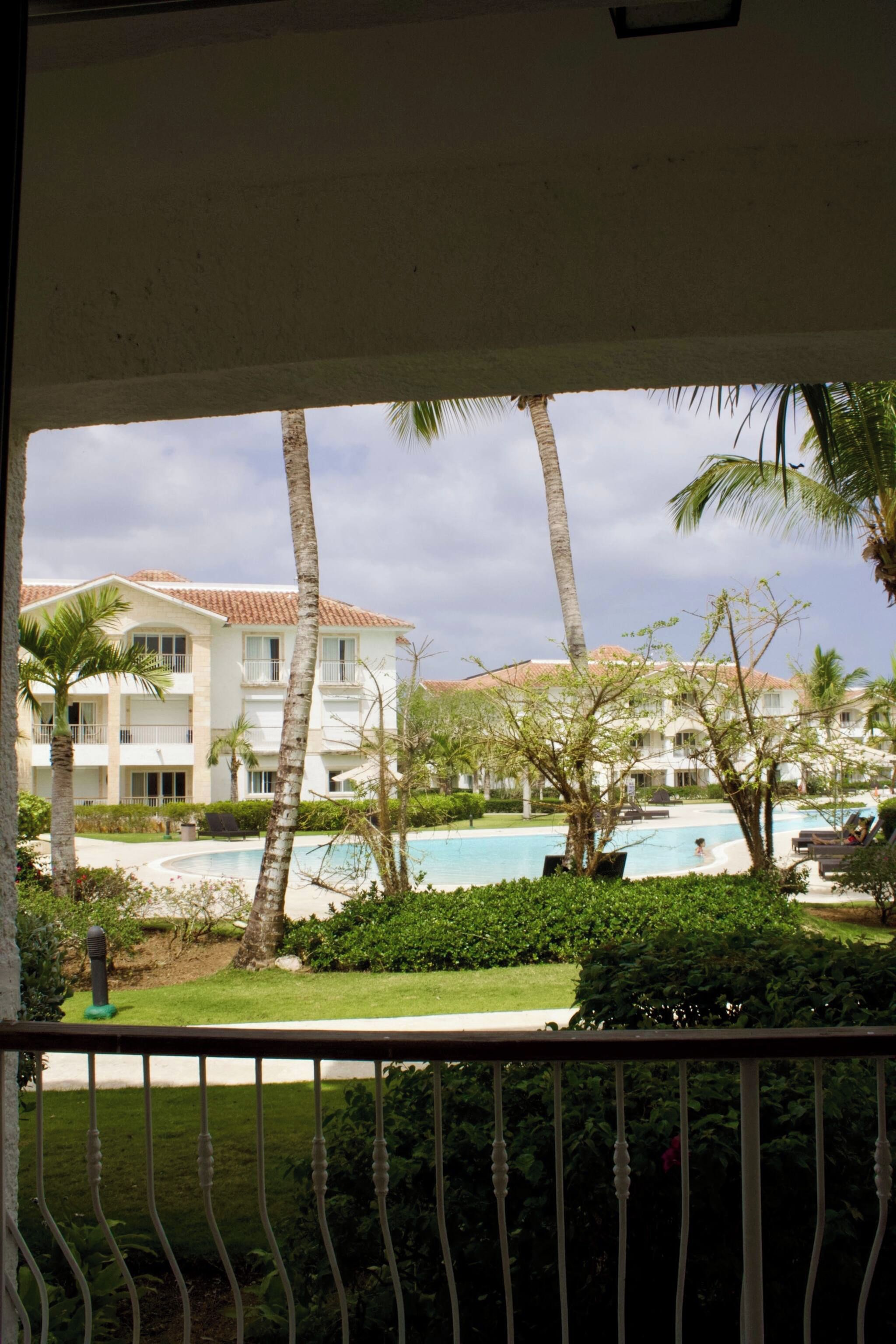 A hotel with a pool, palm trees, and a view of the surrounding landscape.