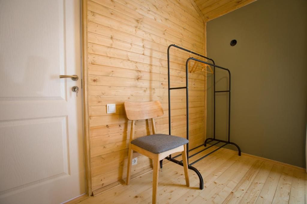 Um quarto com paredes de madeira, uma porta, uma cadeira e uma estante de metal.