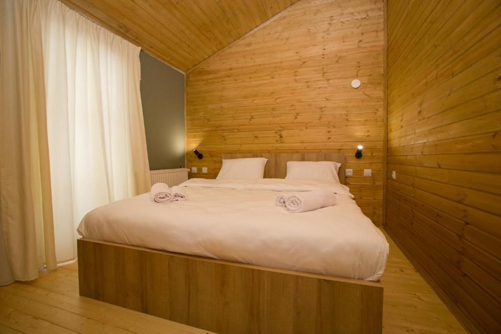 A wooden-paneled bedroom with a bed, two bedside tables, and a wall-mounted light fixture.
