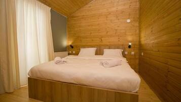A wooden-paneled bedroom with a bed, two bedside tables, and a wall-mounted light fixture.