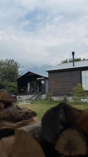 Una cabaña rústica con fachada de madera, una chimenea y un pequeño porche.