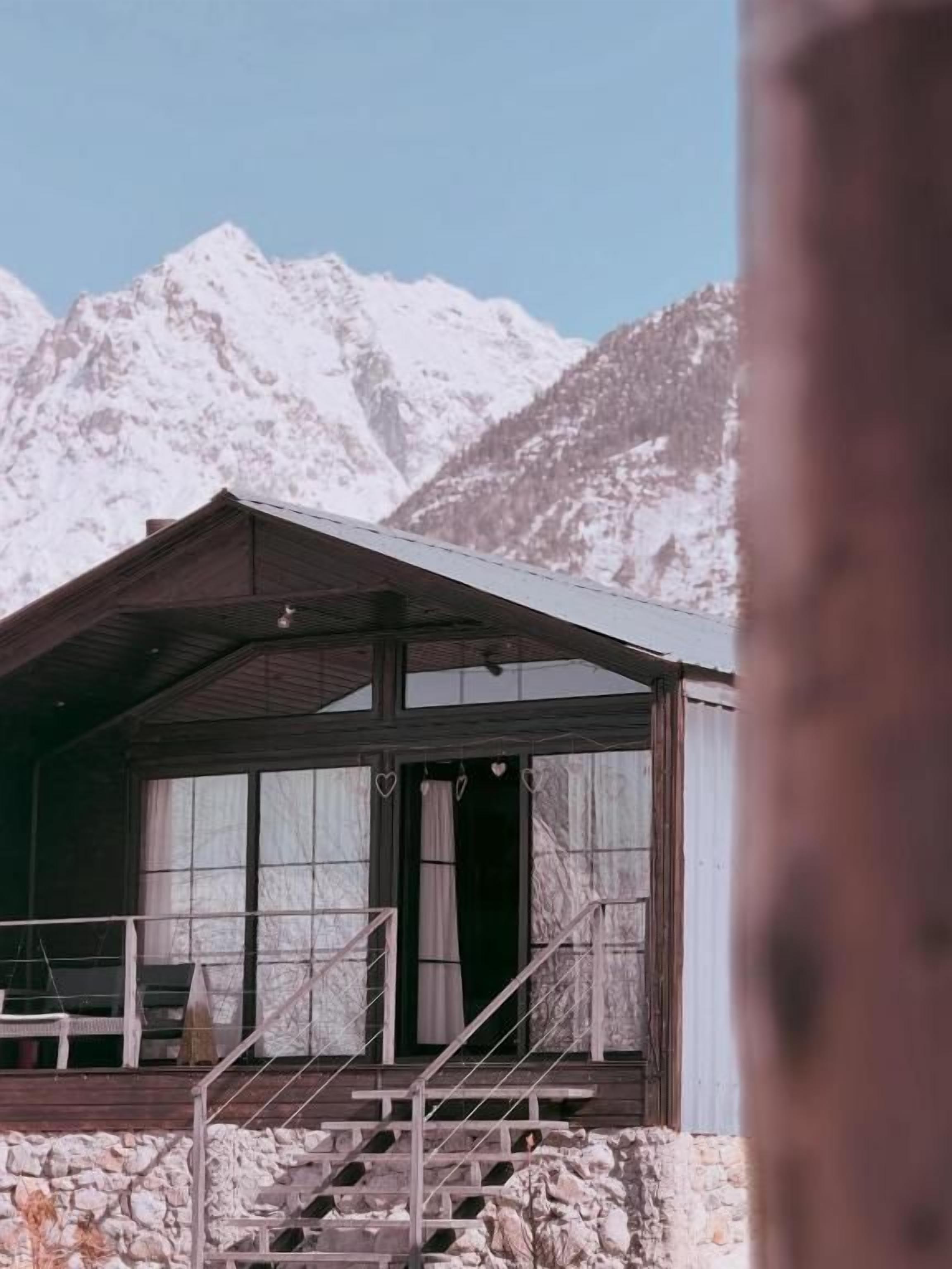 Eine Berghütte mit Steinunterbau, Holzfassade und einem Balkon mit Metallgeländer.