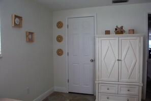 A room with a white door, a white cabinet with drawers, and wall decorations including a clock and circular wall hangings. - Waterfront Oasis - Stock Tank, Pool, Floating Dock & Kayaks (Hudson)