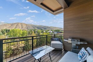 Un balcon avec vue sur les montagnes, une table et un canapé.