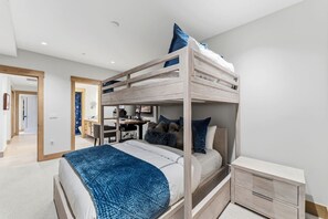 A bunk bed room with a desk, drawers, and a bathroom in the background. - Luxury Condo w/ Resort Amenities, Walk to Gondola (Avon)
