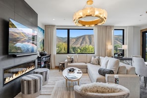 Un salon moderne avec une cheminée, de grandes fenêtres et une vue sur les montagnes.
