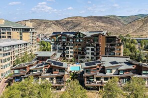 A modern multi-story hotel with balconies, solar panels, and a pool. - Luxury Condo w/ Resort Amenities, Walk to Gondola (Avon)