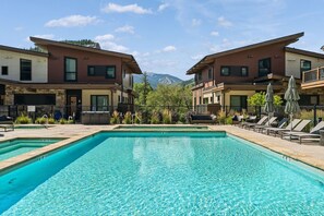 Un espace piscine avec des chaises longues et une vue sur les montagnes en arrière-plan.