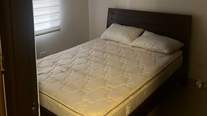 A bedroom with a bed, a window with blinds, and an air conditioning unit on the wall. - Quiet Apartment (Bucaramanga)