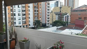 A balcony with potted plants, a view of surrounding buildings, and a tiled floor. - Quiet Apartment (Bucaramanga)