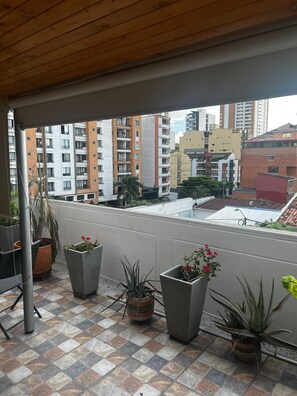 A balcony with potted plants, a view of surrounding buildings, and a tiled floor. - Quiet Apartment (Bucaramanga)