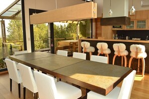 A modern kitchen with a large dining table and white chairs.