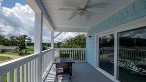 A covered porch with a ceiling fan, a table and chairs, and a view of the neighborhood. - Salt Air & Sunshine – 3BR/3BA Myrtle Beach Townhouse, Steps to the Beach (Myrtle Beach)
