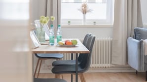 A dining area with a table, chairs, a plate of fruit, and a vase with flowers. - Stylish and Central apt 4 Guests 56sqm top Location (Hannover)
