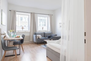 Ett modernt, väl upplyst rum med en matplats, en soffa och en säng.