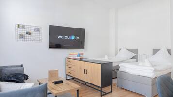Una habitación de hotel moderna con cama, escritorio, televisor y armario.