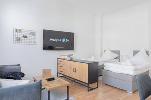 Una habitación de hotel moderna con cama, escritorio, televisor y armario.