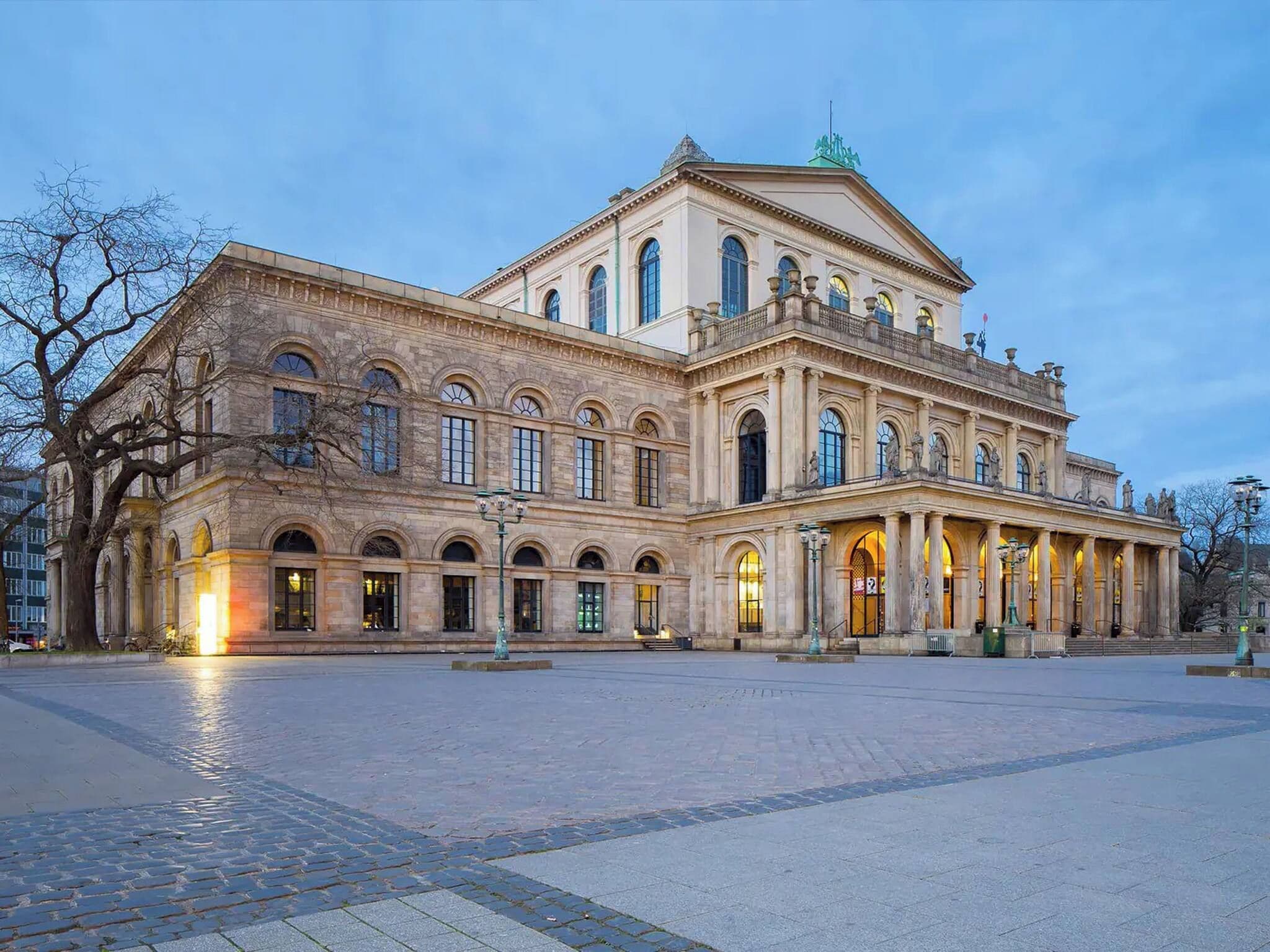 A large, historic building with a symmetrical facade, arched windows, and a central entrance.