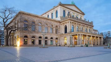 Un edificio grande e histórico con fachada simétrica, ventanas arqueadas y una entrada central.