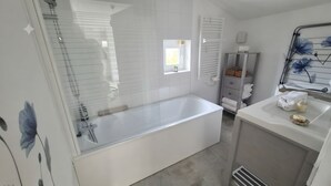 A modern bathroom with a bathtub, a shower, and a vanity with a mirror.