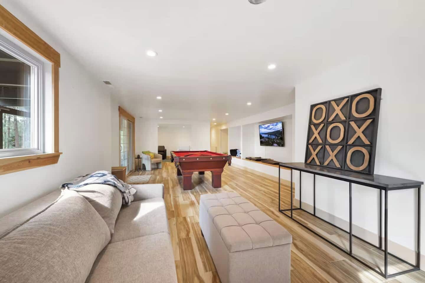 A modern living room with a pool table, a sofa, and a television.
