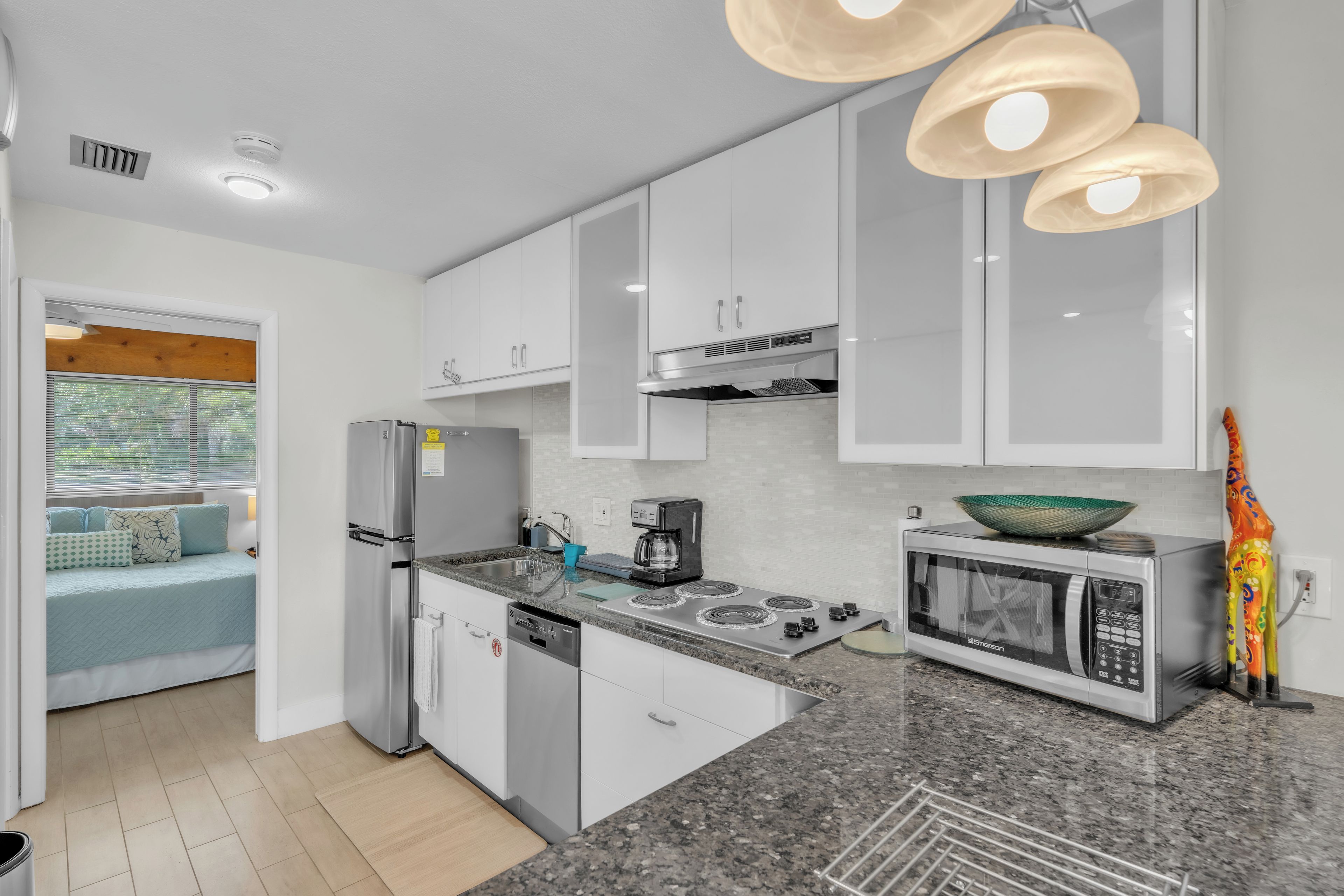 A modern kitchen with white cabinets, a built-in stove, a microwave, and a coffee maker.
