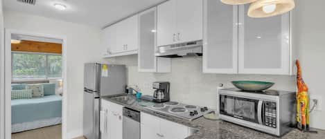 A modern kitchen with white cabinets, a built-in stove, a microwave, and a coffee maker.