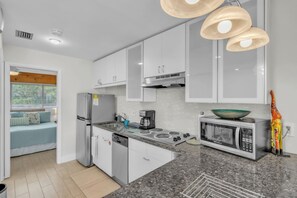 A modern kitchen with white cabinets, a built-in stove, a microwave, and a coffee maker. - Delightful 1-bedroom condo in sunny Sarasota on Golf Course (Sarasota)
