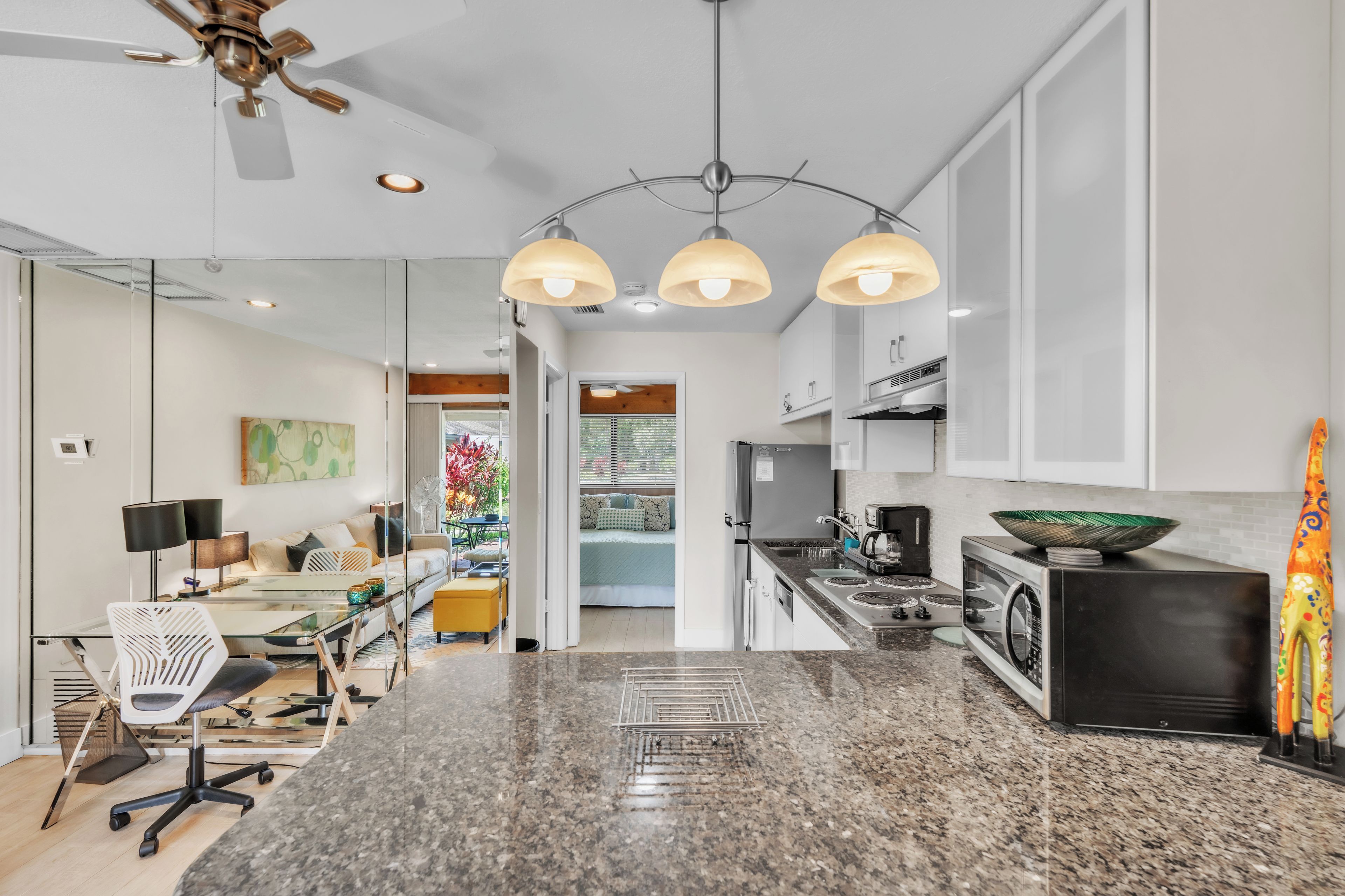A modern kitchen with granite countertops, a black stove, and a dining area with a glass table and chairs.