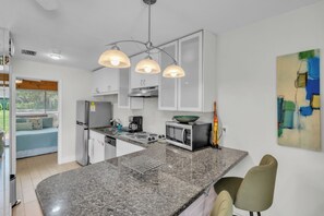 Eine moderne Küche mit Granit Arbeitsplatte, Edelstahlgeräten und Pendelleuchten.