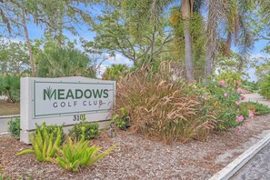 Schild für den Meadows Golf Club mit der Nummer 310, umgeben von Grünflächen und Bäumen.