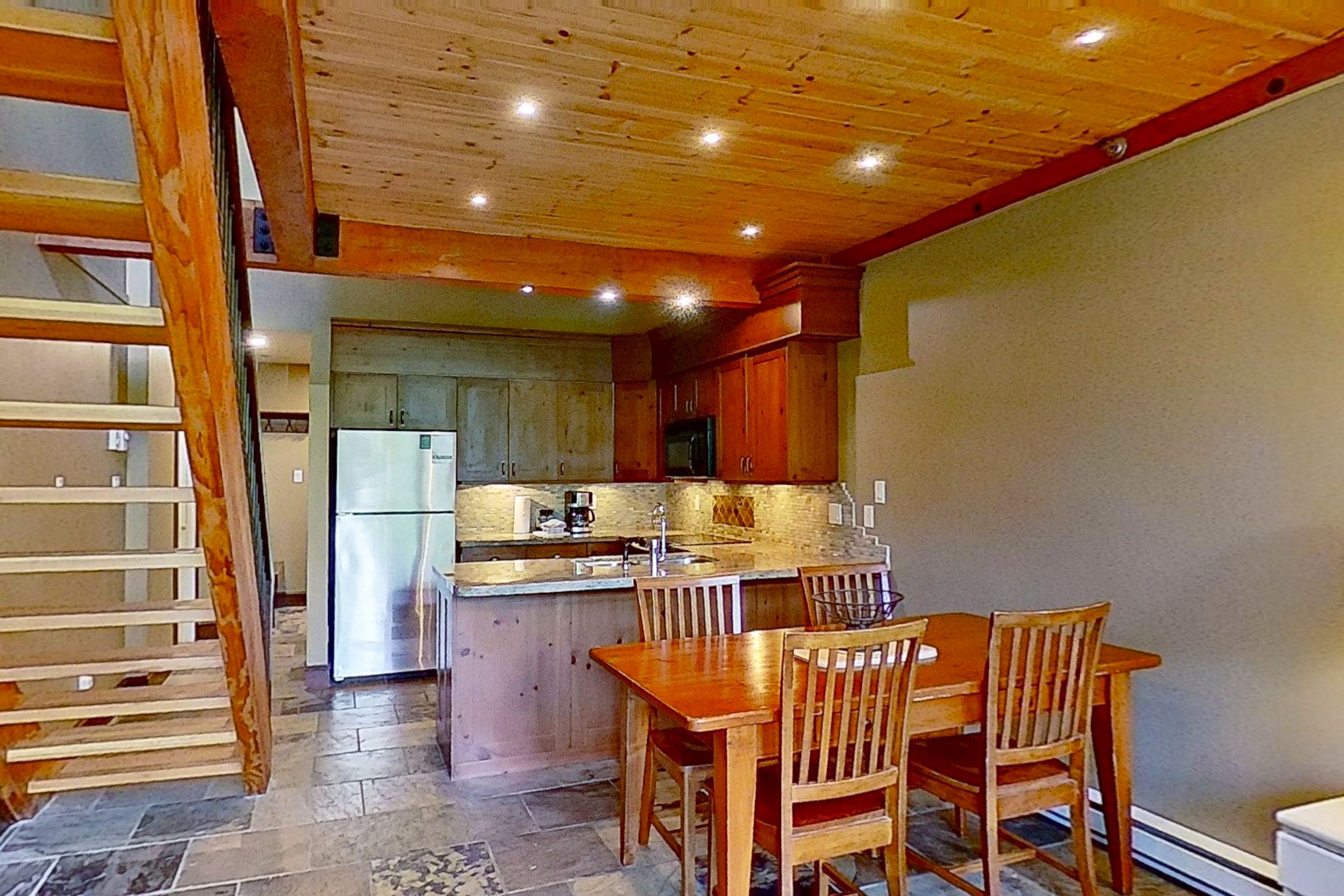 Une cuisine avec des meubles en bois, un îlot central et un coin repas avec des chaises.