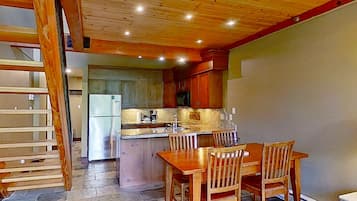 A kitchen with wooden cabinets, a central island, and a dining area with chairs.